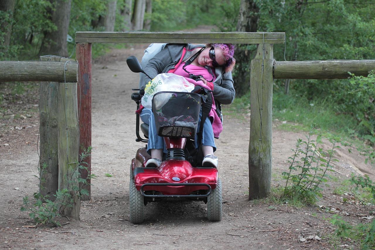 Iemand in een scootmobiel bukt om ergens onderdoor te kunnen